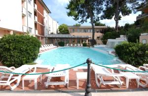 uma piscina com cadeiras brancas e um visor de piscina em Hotel Milano Helvetia em Riccione