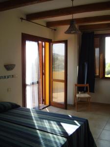 1 dormitorio con 1 cama y puertas correderas de cristal en Agriturismo Cuile de Molino, en Porto Torres