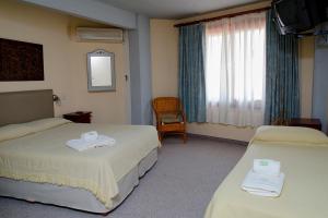 a hotel room with two beds and a window at Hosteria Kaiken II in Villa Gesell