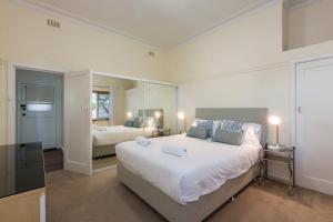 a bedroom with a large white bed and a mirror at Cottesloe Bel-Air Apartment in Perth