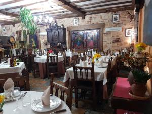 マドリガル・デ・ラ・ベラにあるHosteria Doña Conchiのテーブルと椅子(白いテーブルクロス付)が備わるレストラン