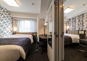 a hotel room with two beds and a desk at APA Hotel Yodoyabashi Kitahama Ekimae in Osaka