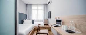 a hotel room with a bed and a desk with a laptop at Hako Hotel in Skudai