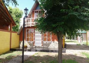 ein Haus mit einem Baum davor in der Unterkunft Cabanas Junto al Rio in Panaholma