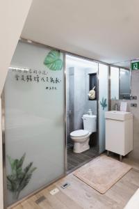 a bathroom with a toilet and a glass shower door at 愛藝宿Art Space in Tainan
