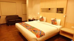 a bedroom with a large bed and a chair at KSquare Hotel in Chennai