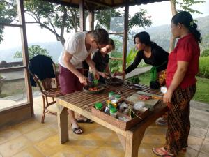 a group of women standing around a table preparing food at Puri Lumbung Cottages Restaurant & Spa Munduk in Munduk
