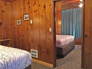 two beds in a room with wooden walls at Park Motel and Cabins in Florence