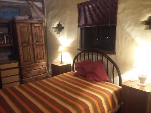 ein Schlafzimmer mit einem Bett mit zwei Lampen und einem Fenster in der Unterkunft Casa Ecológica Rama & Cabaña Rústica in Tandil