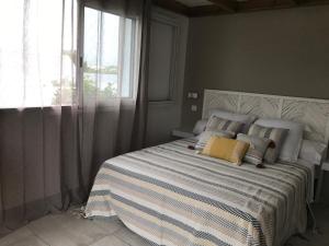 una camera da letto con letto, cuscini e finestra di Bras-Panon: Maison avec vue et piscine 1-4 pers. a Bras-Panon
