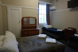 a room with a bed and a couch and a mirror at Castlereagh Hotel in Dubbo
