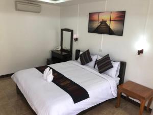 a bedroom with a large white bed and a table at Jasmine Vangvieng Hotel in Vang Vieng