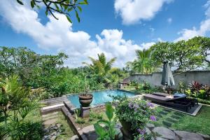 una piscina en un jardín con mesa y sombrilla en Taluh Bebek Ubud Private Villas, en Ubud