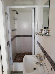 a white bathroom with a sink and a shower at Fairway Guest House in Durban