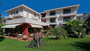 dwoje ludzi jeżdżących rowerami przed budynkiem w obiekcie Hotel Villa Claudia w orbole
