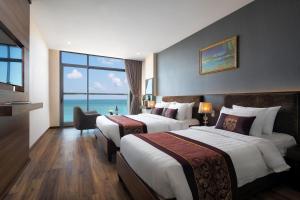 a hotel room with two beds and a view of the ocean at Nolis Hotel in Vung Tau