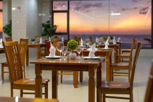 a restaurant with wooden tables and chairs with a view at Nolis Hotel in Vung Tau
