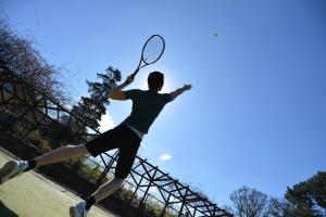 a man swinging a tennis racket on a tennis court at Sheen Falls Lodge in Kenmare