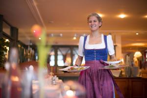 a woman holding two plates of food in a restaurant at Vital Hotel Post in Dienten am Hochkönig +99 photos