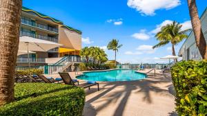 a swimming pool at a resort with chairs and palm trees at Best Western On The Bay Inn & Marina in Miami Beach