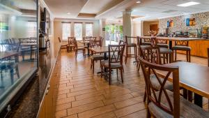 a restaurant with wooden tables and chairs and a bar at Best Western Plus Bradenton Hotel & Suites in Bradenton