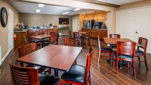 a restaurant with wooden tables and chairs and a kitchen at Best Western Shelbyville Lodge in Shelbyville