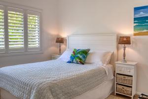Cronulla Beach House B&B في كرونولا: غرفة نوم مع سرير مع مواقف ليلتين ومصباحين