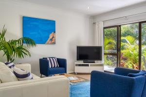 Cronulla Beach House B&B في كرونولا: غرفة معيشة مع تلفزيون وكراسي زرقاء