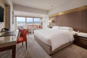 a hotel room with a large white bed and a desk at Grand Hyatt Taipei in Taipei