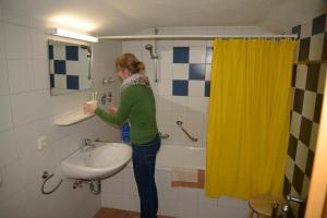 a woman standing in a bathroom brushing her teeth at Alpenhof Punzenlehen in Schönau am Königssee