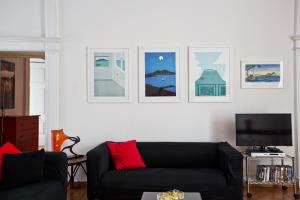 ein Wohnzimmer mit einem schwarzen Sofa und Bildern an der Wand in der Unterkunft Bella Napoli Art Gallery in Neapel