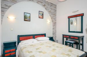 1 dormitorio con 1 cama, 2 mesas y espejo en Polemis Studios & Apartments, en Agia Anna de Naxos