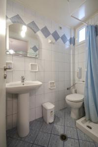 een badkamer met een wastafel, een toilet en een spiegel bij Polemis Studios & Apartments in Agia Anna Naxos