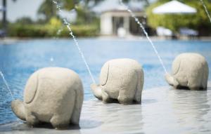 three stone elephants standing in the water near a pool at Taj Bentota Resort & Spa in Bentota