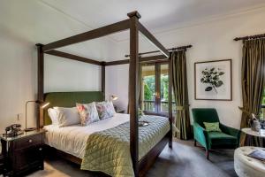 a bedroom with a canopy bed and a green chair at Mount Lofty House & Estate Adelaide Hills in Adelaide