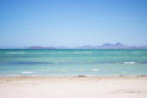 a beach with the ocean and mountains in the background at Apartamentos 525 in Los Alcázares