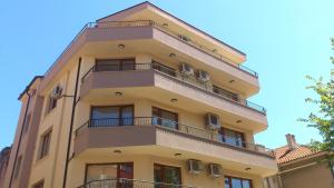 a tall yellow building with balconies on it at Stamatovi Family Hotel in Pomorie +12 photos