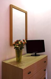 una televisione su un comò con uno specchio e un vaso con fiori di B&B La Terrazza Sul Porto a Trapani