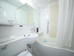 a white bathroom with a sink and a bath tub at APA Hotel Takamatsu Airport in Takamatsu