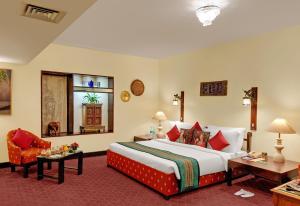 una habitación de hotel con una cama grande y una silla en Ambassador Pallava en Chennai
