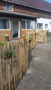 a wooden fence in front of a house with flowers at Hof Heideland 2 - Fenster zum Hof in Eichholz