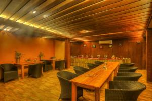 a restaurant with a long wooden table and chairs at The Hermitage Kanatal in Kanatal
