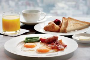 a table with two plates of breakfast food and a cup of orange juice at Arhontiko Hotel in Foinikion