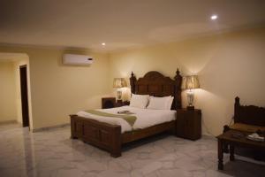 a bedroom with a large bed and two lamps at Grand Millennium Hotel in Lahore