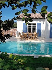 une maison avec une table et des chaises à côté d'une piscine dans l'établissement Lagrange Vacances Carré Beauchêne, à Sainte-Maxime