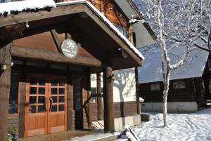 a log cabin with a wooden door in the snow at White Tree Lodge Madarao Tangram in Shinano