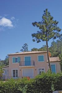 uma casa grande com uma árvore em frente em Lagrange Vacances Carré Beauchêne em Sainte-Maxime