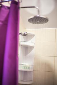 a bathroom with a shower with a purple shower curtain at LURIA apartmens - self check in apartments in Čakovec