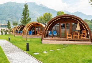 un grupo de cabañas con sillas y mesas en el césped en Campofelice Camping Village en Tenero