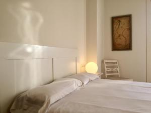 a white bed in a white room with a chair at Plaza in San Sebastián